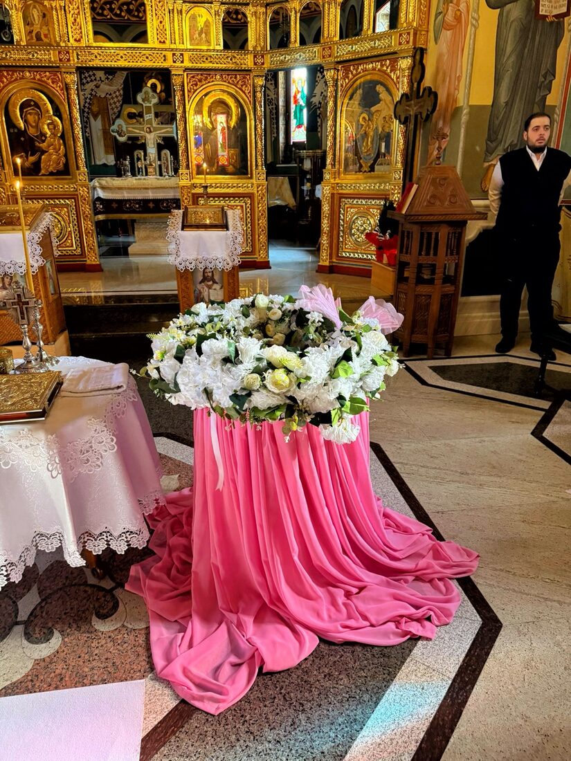 Aranjament floral pe soclu drapat în voal roz pudrat pentru ceremonia din biserică