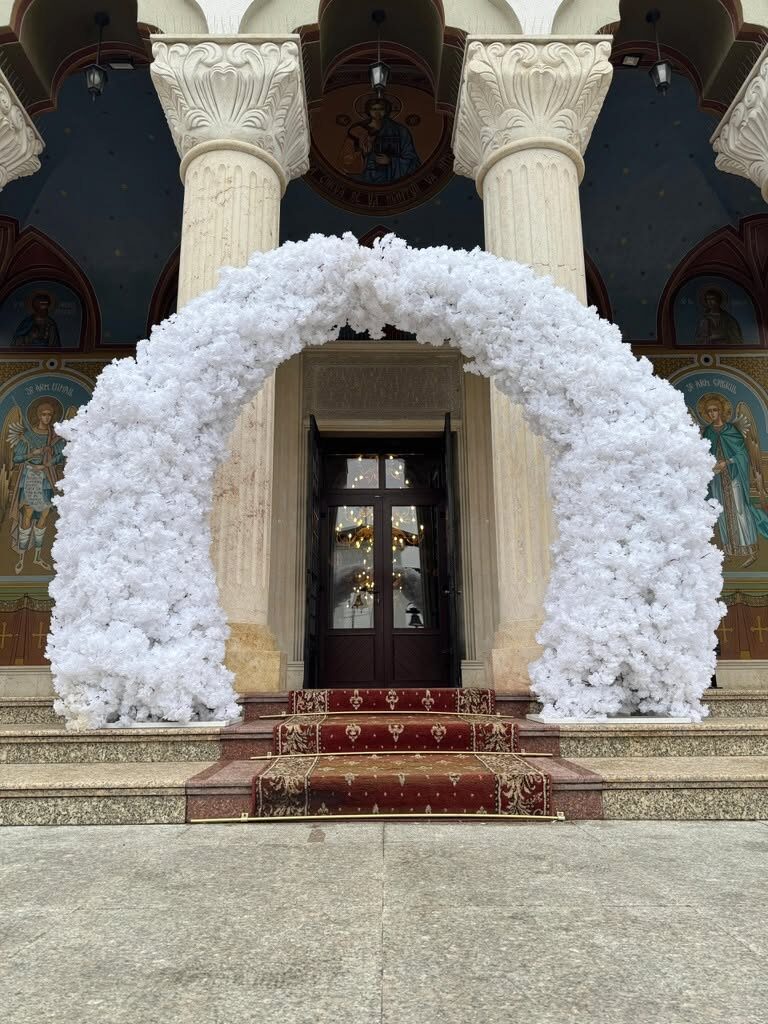 Arcadă florală albă la intrarea bisericii pentru ceremonia de nuntă