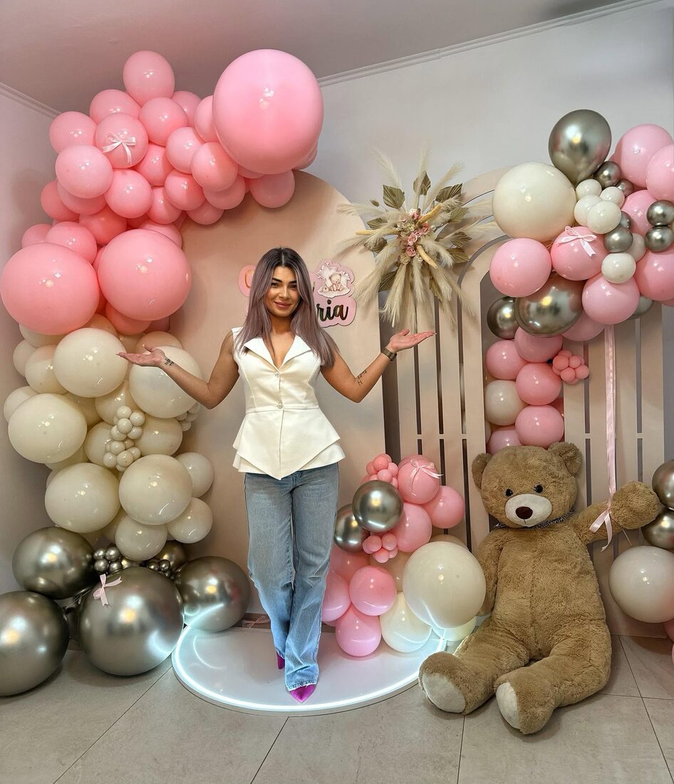 Creatoarea Balooniverse în fața unui decor de botez din baloane roz și crem